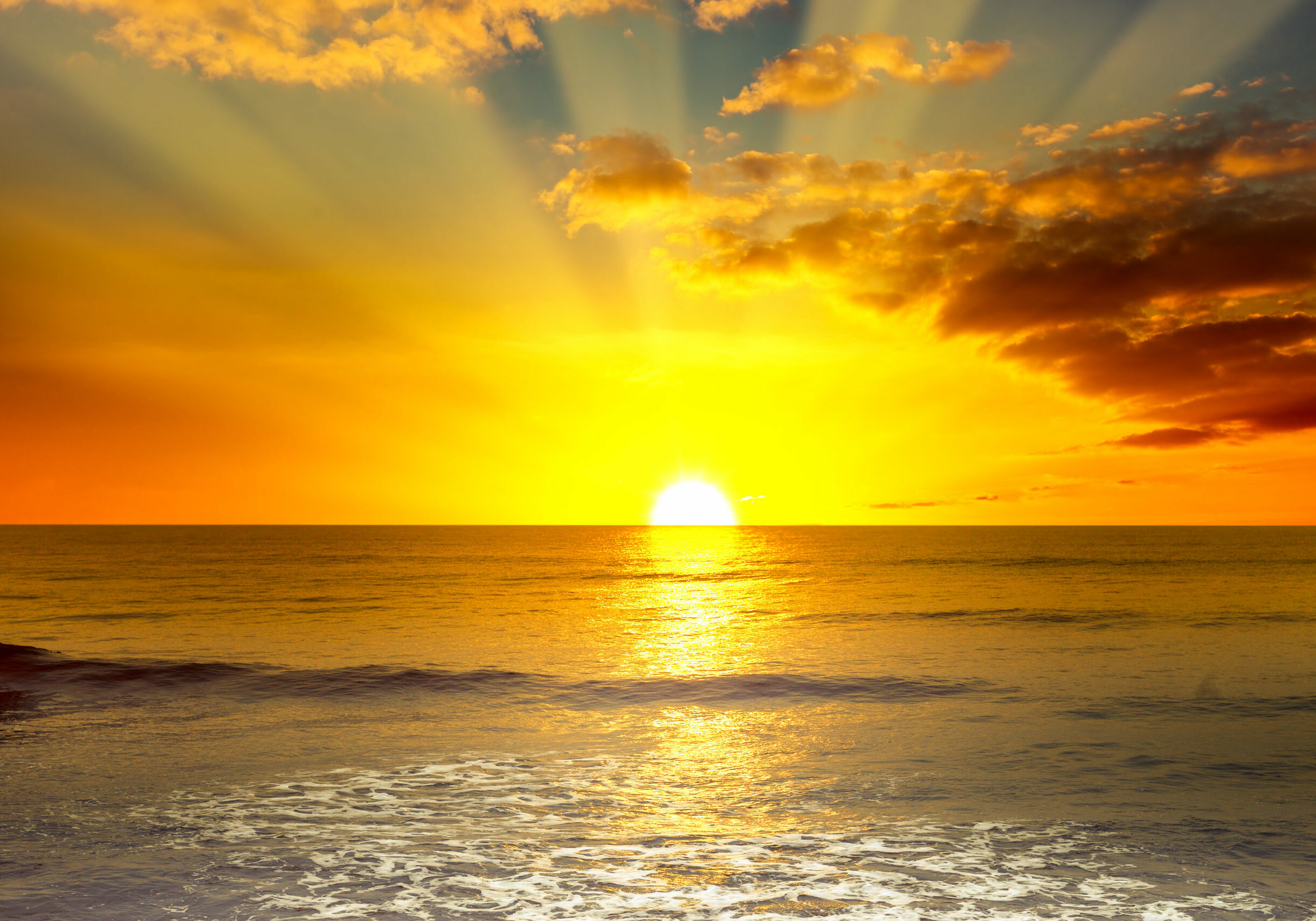 Majestic bright sunrise over ocean and light waves on blue sea.