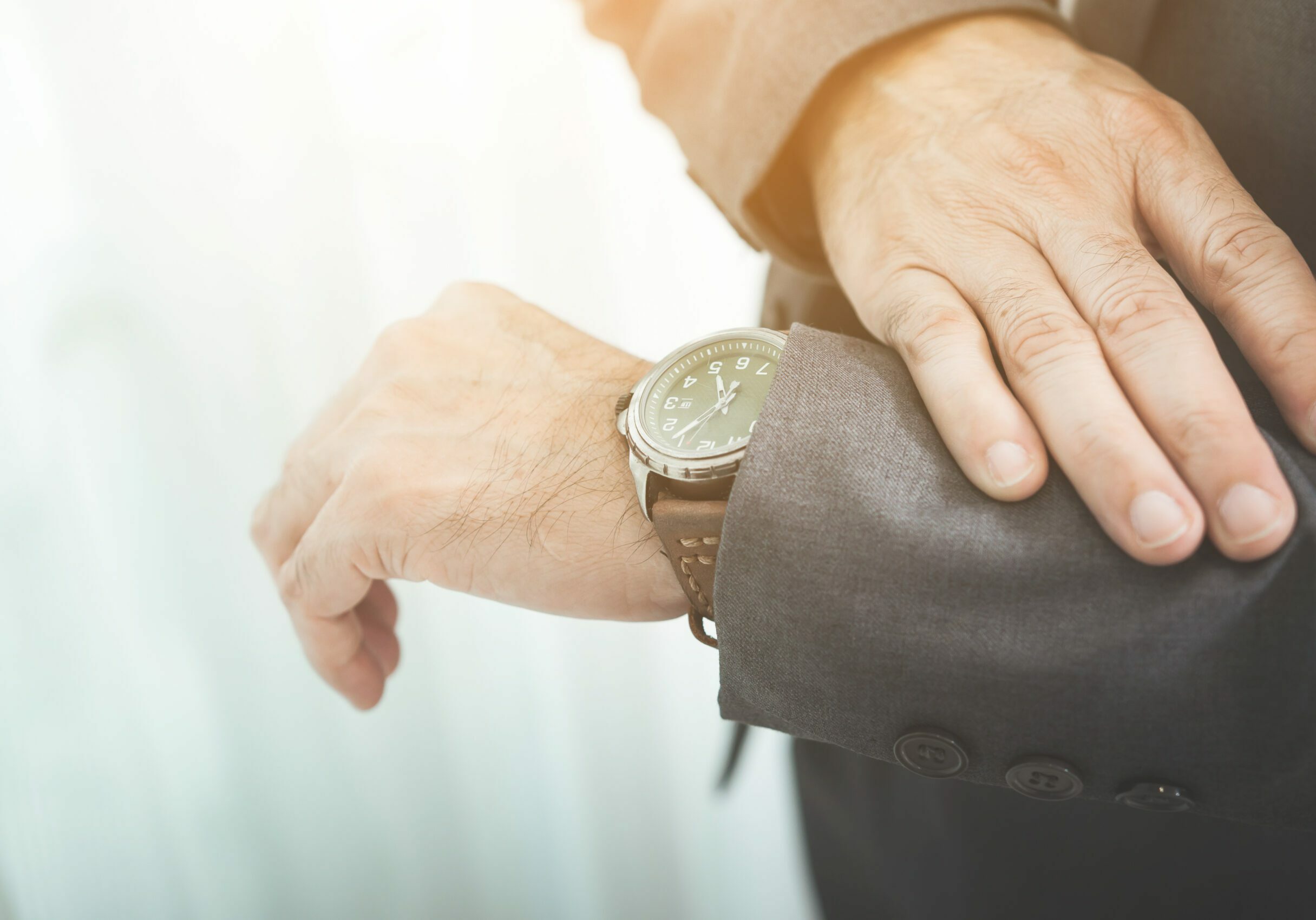 Close up of businessman in grey suit looking watch.